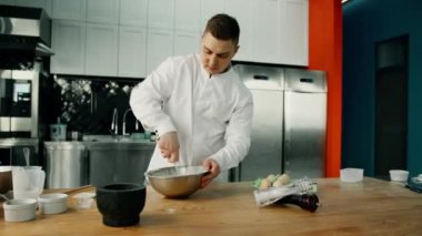 Erkek şef, profesyonel mutfaktaki kaseye krep karıştırıyor..