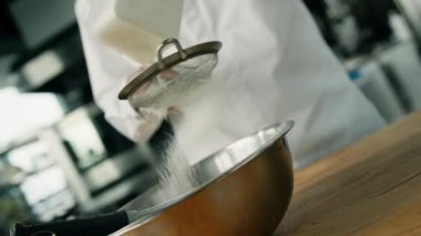 Elle tutulan erkek şef, profesyonel bir mutfakta un topluyor. Restoranda krep yapmak..