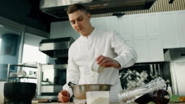 Erkek aşçının orta pozu profesyonel bir mutfakta tavaya yumurta koyar. Lokantada krep yapma süreci.