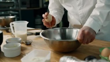 Erkek aşçı, profesyonel bir mutfakta tavada yumurta kırıyor. Lokantada krep yapma süreci.