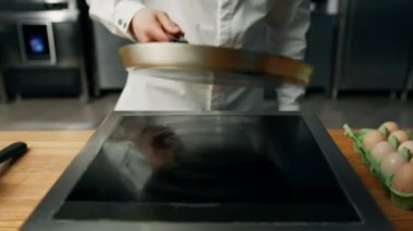 Profesyonel mutfak: Aşçı profesyonel sobanın sıcak tavasına yağ ekliyor