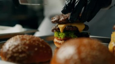 Profesyonel mutfak: şef hamburgeri malzemeler ekleyerek hazırlar