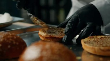 Profesyonel mutfak: şef hamburgeri malzemeler ekleyerek hazırlar