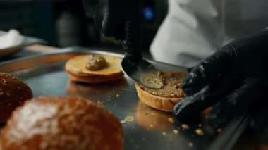 Profesyonel mutfak: şef hamburgeri malzemeler ekleyerek hazırlar