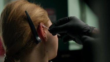 Piercing stüdyosunun iç mekanı - piercing ustası kızı deliyor, kulaklarını deliyor