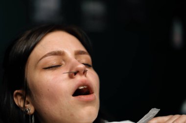 Piercing stüdyosu. Bir usta bir kızın burnunu deliyor.