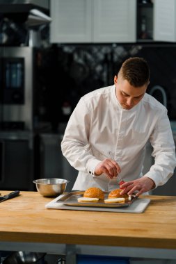 Bir şef, profesyonel mutfak gastronomisinde fırçayla hamburger pişirir.