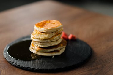 Kahvaltı için masasında çilek ve bal olan krep yığınlarının görüntülerini kapat.