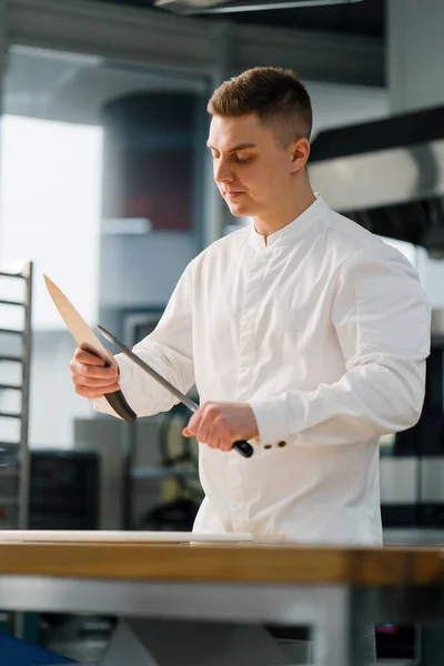 シェフがプロのキッチンのプロの研磨ツールで調理する前にナイフを研ぐ — ストック写真
