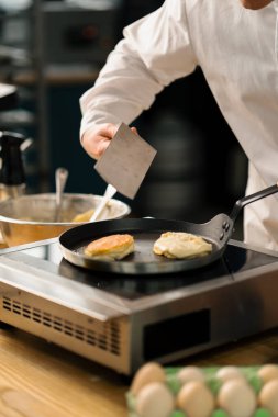 Bir restoranın mutfağında profesyonel bir şef kahvaltı için krep hazırlar. Mutfak tarifi fırında kızartma tavası