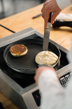 Bir restoranın mutfağında profesyonel bir şef kahvaltı için krep hazırlar. Mutfak tarifi fırında kızartma tavası
