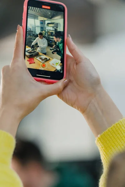 ブロガーは食べ物の写真を撮るスマートフォンでハンバーガーを作るプロセスを撮影 — ストック写真