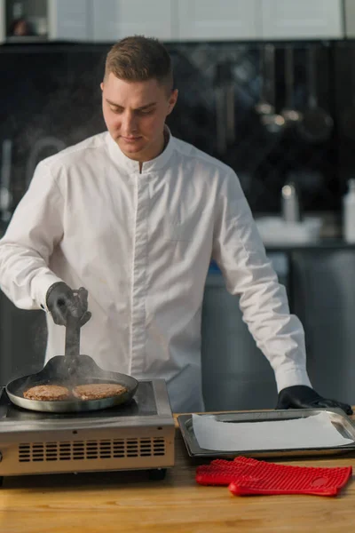 黒手袋のシェフは プロのキッチンでおいしいハンバーガーのパティホットパンを準備 — ストック写真