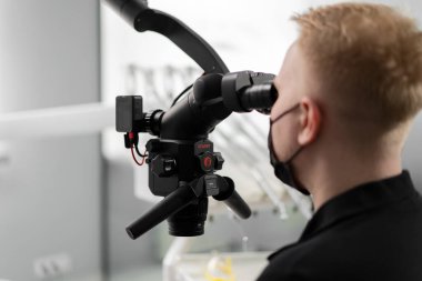 Diş hekimliği bir hastayı mikroskopla muayene eder. Diş hekimliği, diş sağlığı kliniği