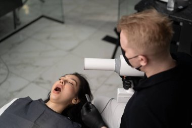 Diş hekimi hastanın dişlerinin röntgenini çeker.