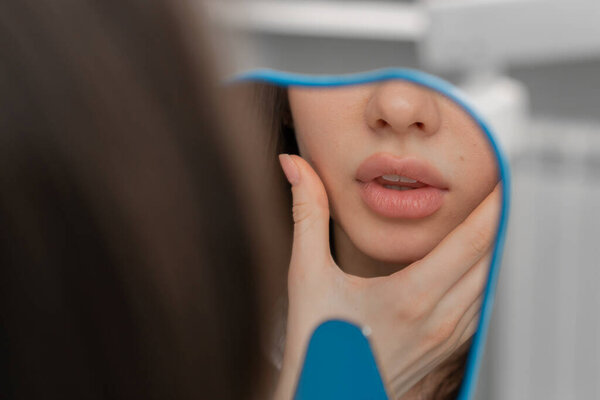 Dentistry a satisfied patient looks in mirror at his teeth