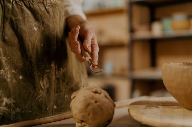 Potter 'ın atölyesi, usta kilin elinde kil işlemek için bir araç masanın üzerinde yatıyor.