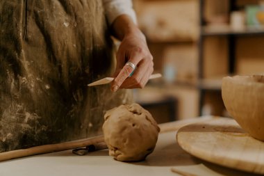Potter 'ın atölyesi, usta kilin elinde kil işlemek için bir araç masanın üzerinde yatıyor.
