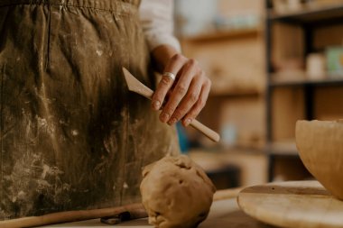 Potter 'ın atölyesi, usta kilin elinde kil işlemek için bir araç masanın üzerinde yatıyor.