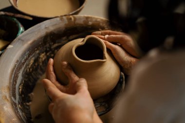 Çömlekçilik atölyesi çömlekçiye çömlek çifti heykeli yapmayı öğretiyor.