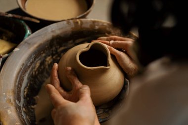 Çömlekçilik atölyesi çömlekçiye çömlek çifti heykeli yapmayı öğretiyor.