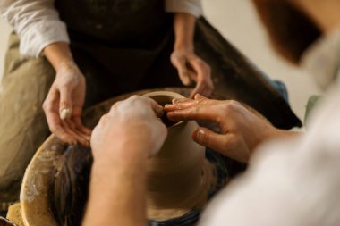 Çömlekçilik atölyesi çömlekçiye çömlek çifti heykeli yapmayı öğretiyor.