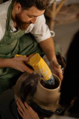 Bir çömlekçi çömlek atölyesindeki kil sürahisini kurutur.