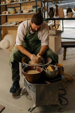 Çömlekçi çömlek atölyesinde çömlekçi çarkına sürahi heykeli yapar.
