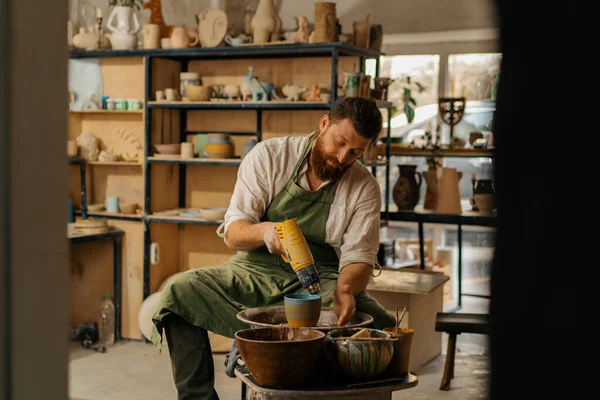 陶工在陶器车间里用烘干机擦干漆壶 — 图库照片