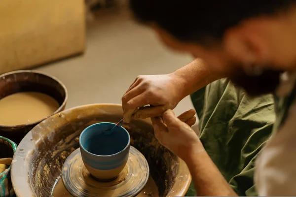 陶芸工房の陶芸家は ろくろに筆と絵具でジャグを描く — ストック写真