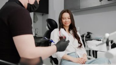 Diş hekimindeki bir diş hekimi hastaya dişlerini nasıl fırçalayacağını söyler.