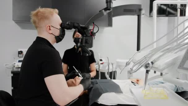 Klinice Dentystycznej Dentysta Bada Pacjenta Bólem Zęba Pod Mikroskopem — Wideo stockowe