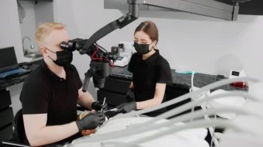 Diş hekiminde bir dişçi mikroskop altında diş ağrısı olan bir hastayı muayene eder.