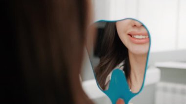 Diş kliniğinde tatmin olmuş bir hasta ameliyattan sonra dişlerini muayene eder.