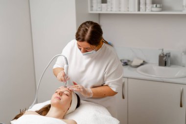 Eldivenli güzellik uzmanı, kozmetoloji kliniğinde cilt bakımı ve cilt temizliği yapıyor. Modern insanlar için profesyonel nemlendirici ve gençleştirici donanım prosedürleri uyguluyor.