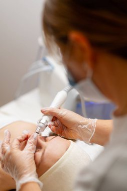 Eldivenli güzellik uzmanı, kozmetoloji kliniğinde cilt bakımı ve cilt temizliği yapıyor. Modern insanlar için profesyonel nemlendirici ve gençleştirici donanım prosedürleri uyguluyor.
