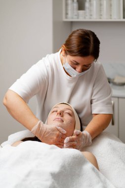 Makyaj için spa salonundaki kadın yüz ve boyuna bakımı için güzel bir kadın görünüşüne özen gösterir.