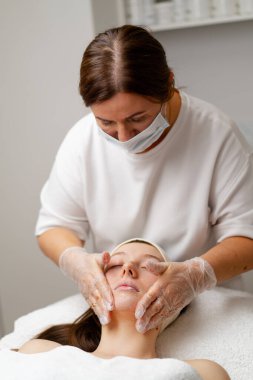 Makyaj için spa salonundaki kadın yüz ve boyuna bakımı için güzel bir kadın görünüşüne özen gösterir.