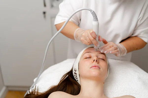 stock image Beautician in gloves conducts vacuum cleaning and polishing face skin young woman in cosmetology clinic Professional moisturizing and rejuvenating hardware procedures for modern people