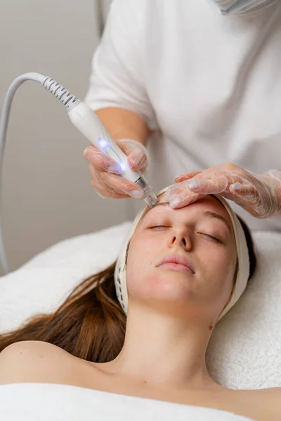 stock image Beautician in gloves conducts vacuum cleaning and polishing face skin young woman in cosmetology clinic Professional moisturizing and rejuvenating hardware procedures for modern people