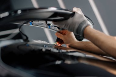 Bir tamirci modern lüks araba tamirhanesine spoiler monte ediyor.