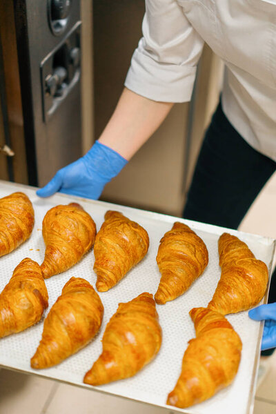 Kitchen in the bakery - ready-made croissants are taken from oven