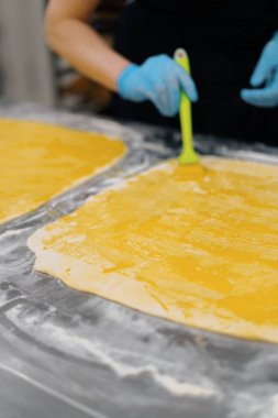 Fırındaki mutfak... Cinnabon pişirme işlemi, kadın fırıncı yumurta sarısı kullanır.