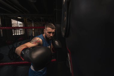 Bir boksör boks yaparken yumruklarını kum torbasına vurur.