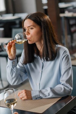 Bir otel restoranında bir kadın yakın plan beyaz şarap içer.