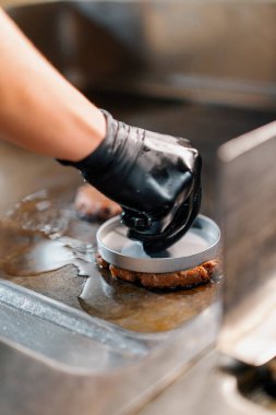 Restoranın mutfağındaki aşçı hamburgerler için pirzola yapar burgerleri ezer biftekleri ezer