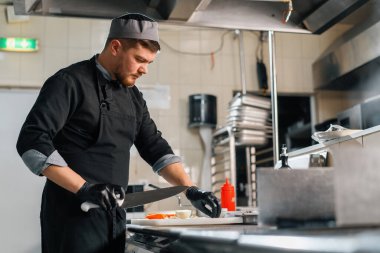 Otel restoranında profesyonel mutfak bıçaklı şef sebze burgeri keser.