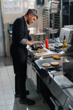 Otel restoranında profesyonel mutfak bıçaklı şef sebze burgeri keser.