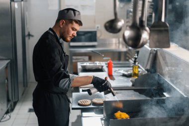 Otel lokantasında profesyonel mutfak. Mutfak meşaleli, kahverengi peynirli burger köftesi.