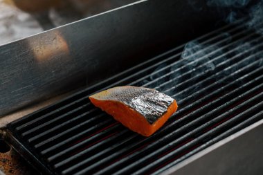 Bir otel restoranında profesyonel bir mutfak. Izgarada taze somon balığı var.